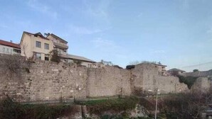 A stone wall with buildings on top, likely part of a historical site or fortification. - Çarşı Marin Denizer Pension (Amasra)