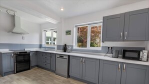 A modern kitchen with grey cabinets, a built-in oven, and a microwave.