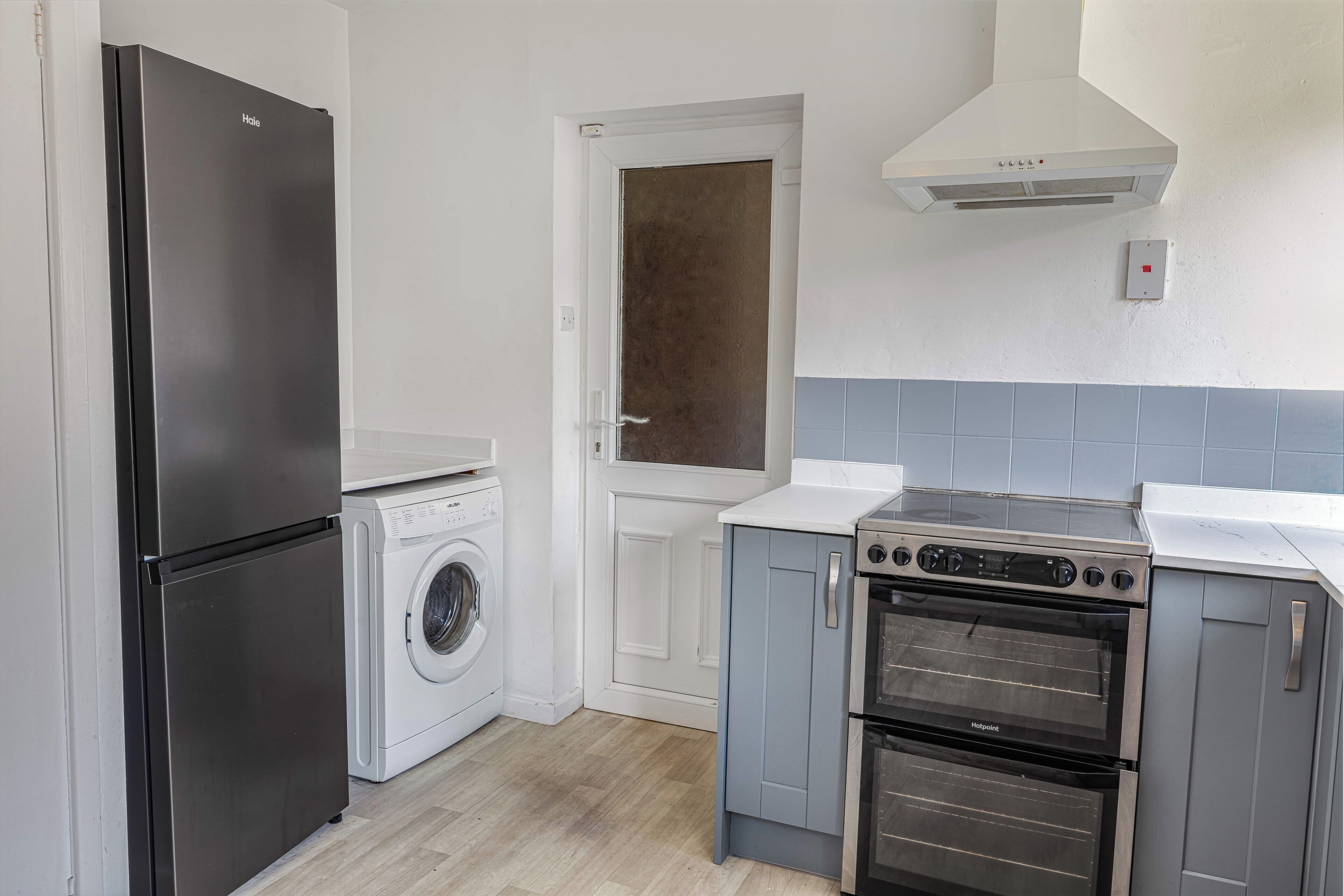 Une cuisine compacte équipée d’un réfrigérateur noir, d’un lave-linge, d’une cuisinière et d’un four à micro-ondes.