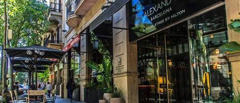 A double-leveled hotel entrance with outdoor seating and potted plants.