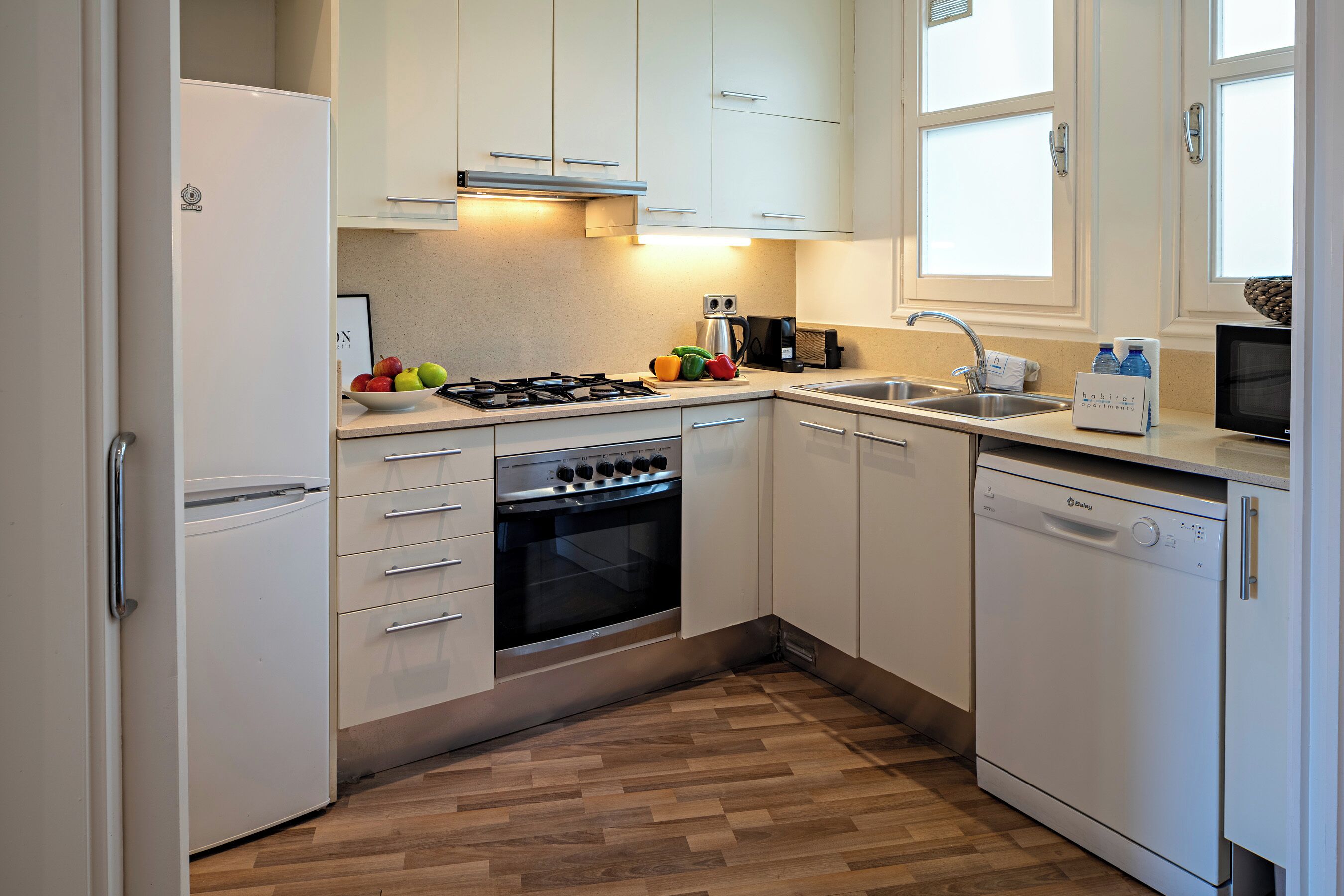 Een moderne keuken met witte kastjes, een gasfornuis, een oven, een vaatwasser en een spoelbak.