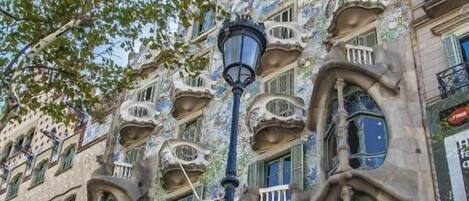 Un edificio con detalles arquitectónicos singulares, incluyendo balcones de formas orgánicas y una escalera que conduce a la entrada.