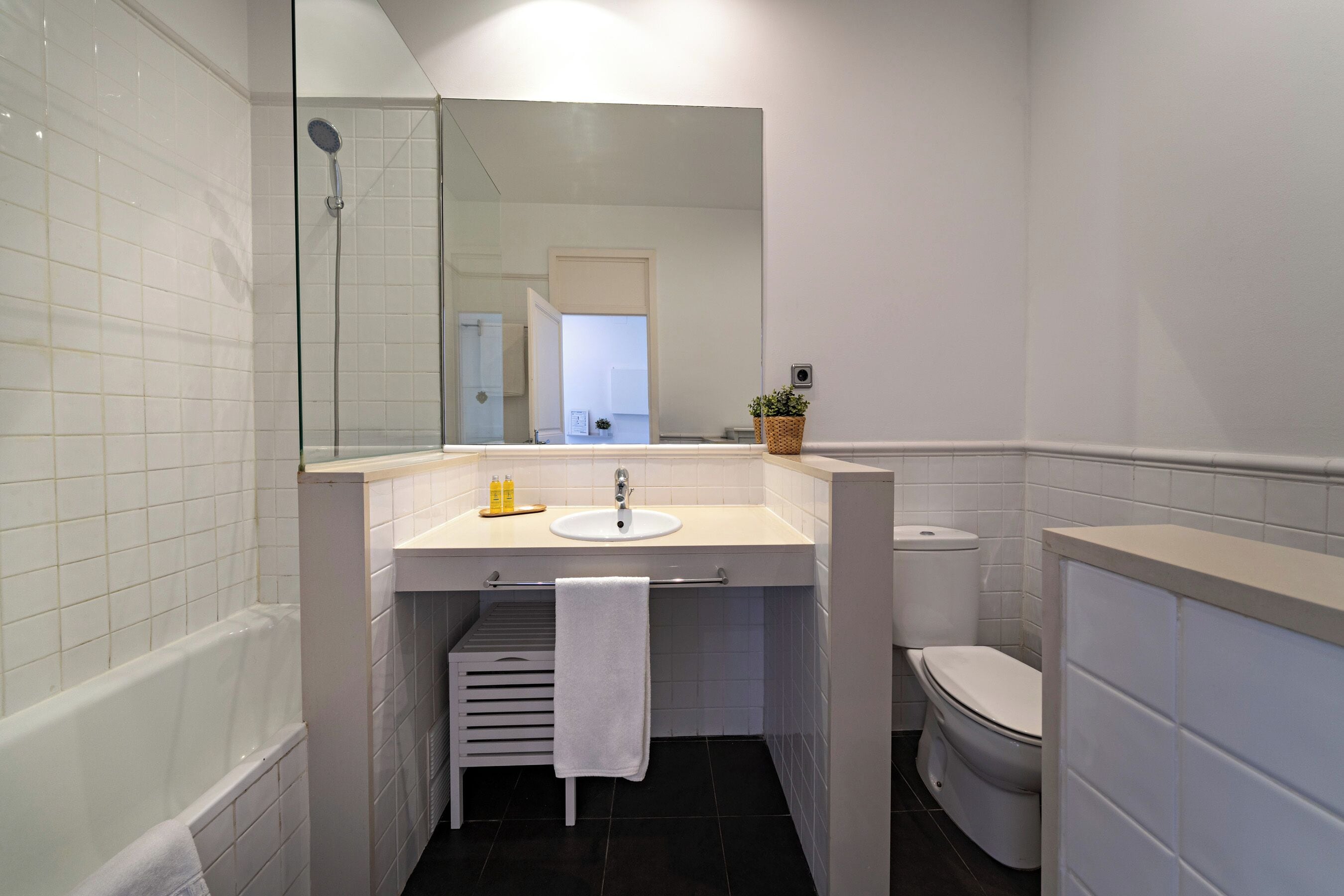 A modern bathroom with a glass-enclosed shower, a white sink, and a toilet.