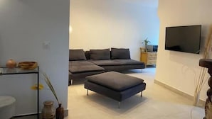A modern living room with a sectional sofa, a flat-screen TV, and a minimalist decor. - La villa au palmier - 10bed, 2bath, roof terrace (Perpignan)