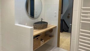 A bathroom with white tiled walls, a round mirror, a wooden vanity with a stone basin, and built-in shelves. - La villa au palmier - 10bed, 2bath, roof terrace (Perpignan)