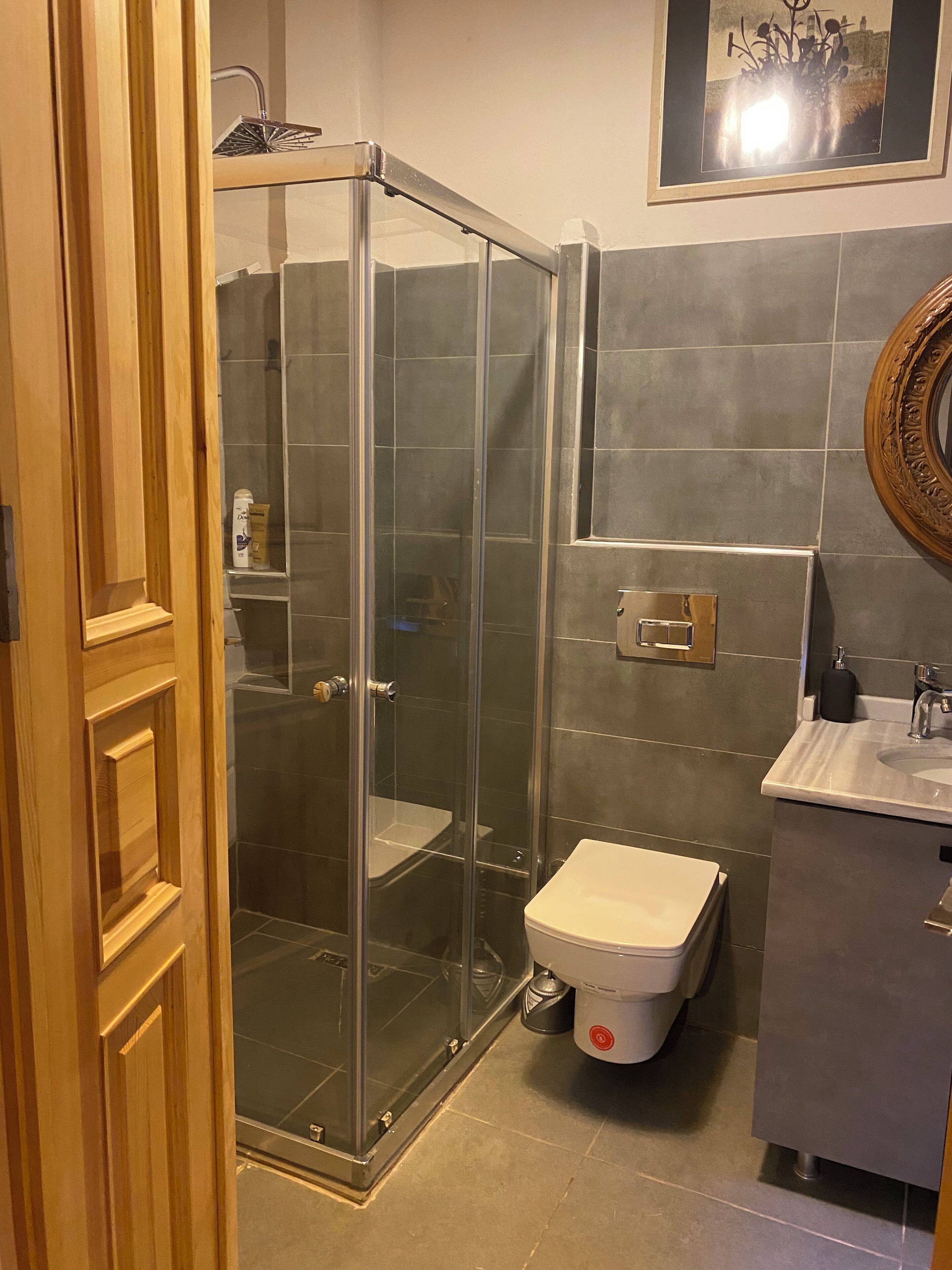 A bathroom with a glass-enclosed shower, a toilet, and a sink.