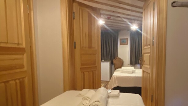 A hotel room with wooden paneling, a bed with neatly folded towels, and a view of another room with a bed and a chair. - HanFlats Hotel (Istanbul)