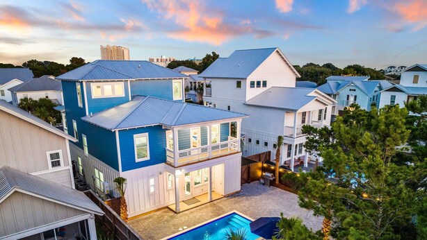 Un quartier résidentiel comprenant plusieurs maisons, une piscine et un balcon avec des meubles pour se détendre en plein air.