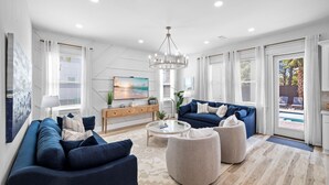 Un salon moderne avec un canapé bleu, une table basse ronde et un lustre.