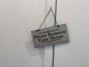 Una señal en la pared que dice: 'Por favor, quítese los zapatos'.