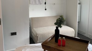 A compact room with a bed, a small table, a hanging light fixture, and a coat rack. - Posh Pad Woolton Village (Liverpool)