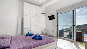 A bedroom with a bed, a wardrobe, a TV, and a balcony with a view. - Villa Sapfo in Lefkada (Lefkada)