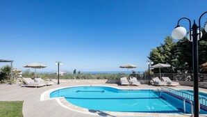 Ein klarer, blauer Himmel, ein Schwimmbecken mit Liegestühlen und Sonnenschirmen.