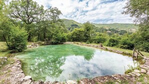 A clear outdoor swimming pool surrounded by lush greenery and stone walls. - Baciola in Ortignano Raggiolo (Ortignano Raggiolo)