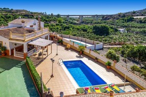 A two-story house with a swimming pool, outdoor seating, and a view of a bridge and greenery. - Villa Maria Gomez in Frigiliana (Nerja)