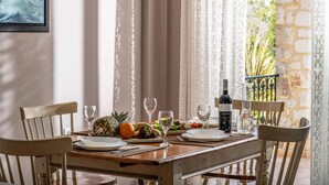 Une table à manger dressée avec des assiettes, des verres et une bouteille de vin, agrémentée d’une composition de fruits tropicaux et d’un tableau accroché au mur.
