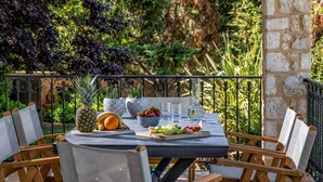 Un espace extérieur aménagé pour prendre les repas, avec une table dressée pour deux personnes, entourée de chaises.