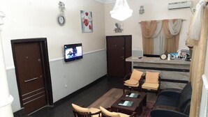 A living room with a sofa, two armchairs, a coffee table, a TV, and a dining area with a table and chairs. - Howard Lodgings and Leisure (Calabar)