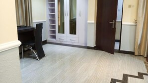 A room with a desk, a wardrobe with mirrored doors, and a door leading to another room. - Howard Lodgings and Leisure (Calabar)