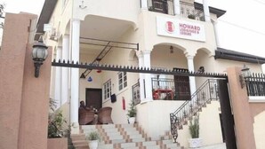 A two-story Howard Lodgings & Leisure building with a gated entrance, a staircase leading to the entrance, and a balcony on the upper floor. - Howard Lodgings and Leisure (Calabar)