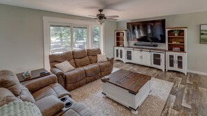 A living room with a brown leather sofa, a wooden coffee table, and a TV on a white cabinet. - Serenity On Rice Lake (Brainerd)