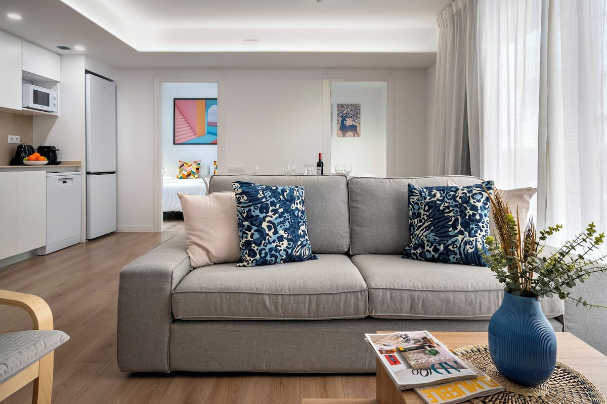 Un salon moderne avec un canapé gris, un vase bleu contenant des plantes et un magazine sur la table basse.
