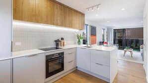 Una cocina moderna con una isla central, electrodomésticos integrados y una pared decorativa de madera.