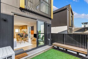 Un immeuble résidentiel moderne à deux étages, doté d’une cuisine et d’un coin repas ouverts, d’un balcon et d’une cour arrière clôturée.