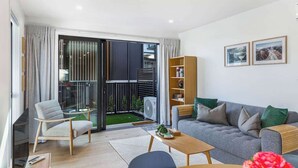 Una sala moderna con sofá, sillones, una mesa de centro y una estantería.