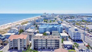 Eine Küstenstadt mit Strand, mehrstöckigen Gebäuden und wolkenlosem Himmel.