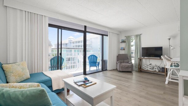 Ein modernes Wohnzimmer mit einer Couch, einem Fernseher und einem Balkon mit Sitzgelegenheiten.