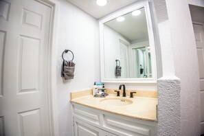 A bathroom with a beige countertop, a sink, a mirror, and a towel rack. - Princesa de Penasco B-407 (2Bedroom-2Bathroom) By FMI Rentals (Puerto Peñasco)