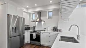 A modern kitchen with stainless steel appliances, a gas stove, a built-in oven, and a sink with a modern faucet. - Miramar Oasis! Ocean View, Hot Tub, Steps2Beach, Roof Deck, Fire Pit, Coastal Trail (El Granada)