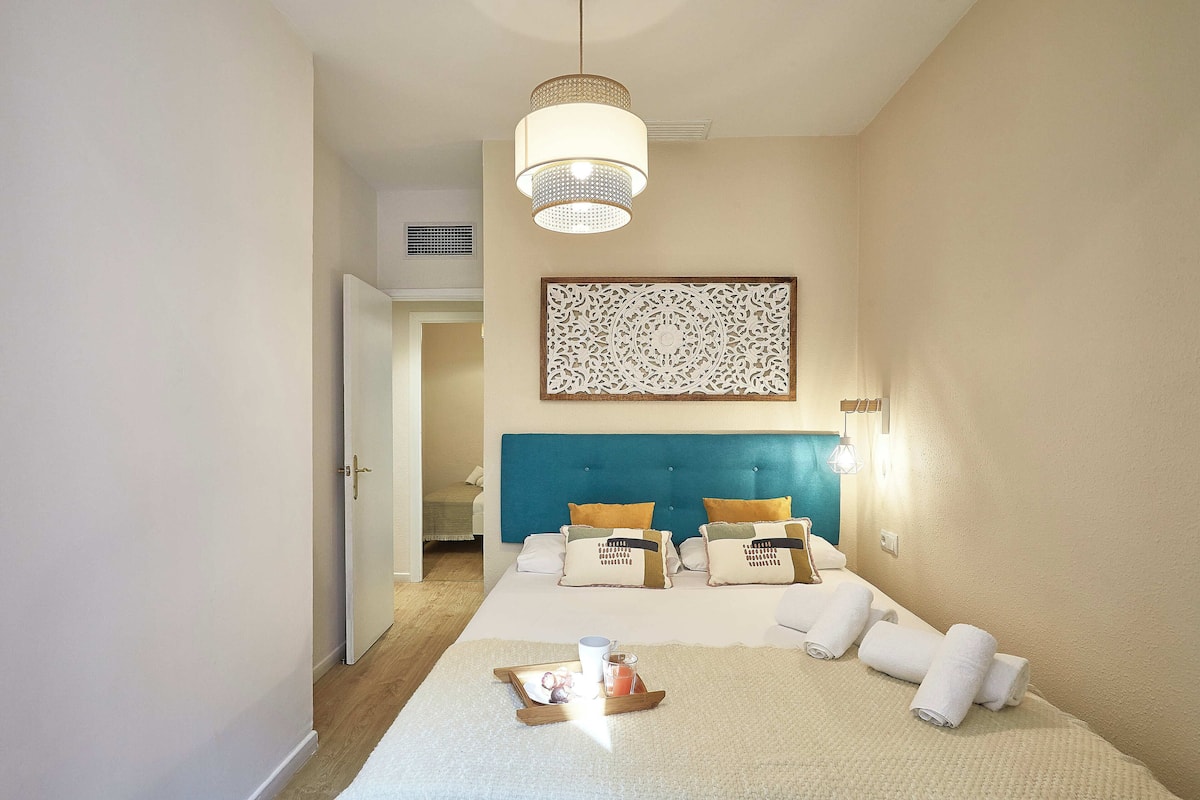 Ett hotellrum med en stor säng, en blå sänggavel och en dekorativ väggdekoration.