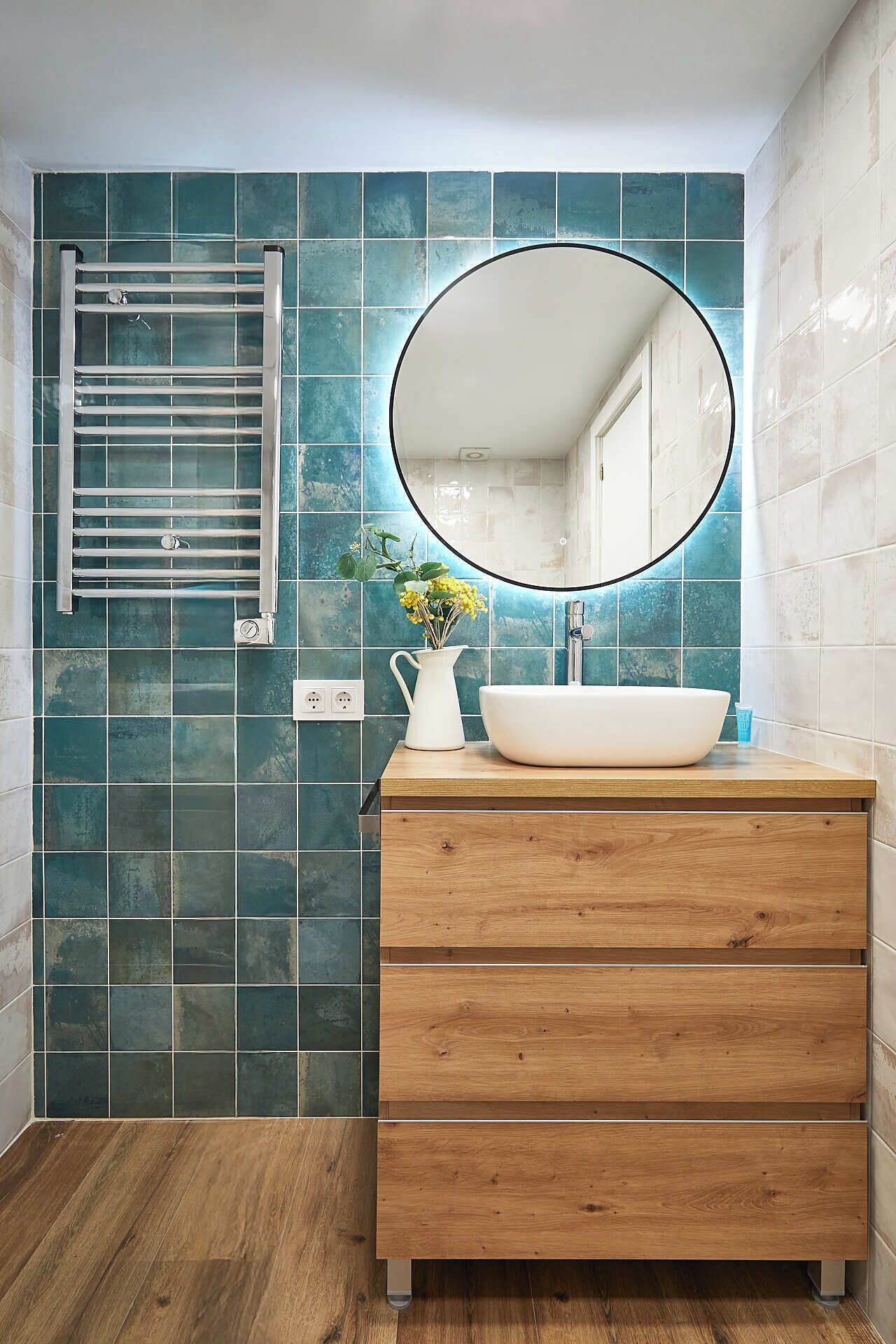 A bathroom with a wooden vanity, a white sink, and a mirror.