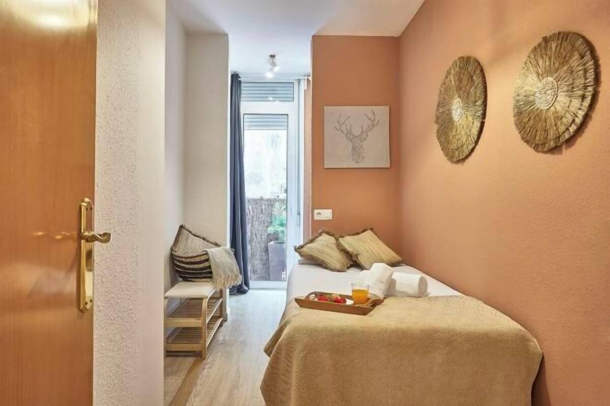 A cozy bedroom with a bed, a bedside table, a tray with breakfast, and a door leading to a balcony.