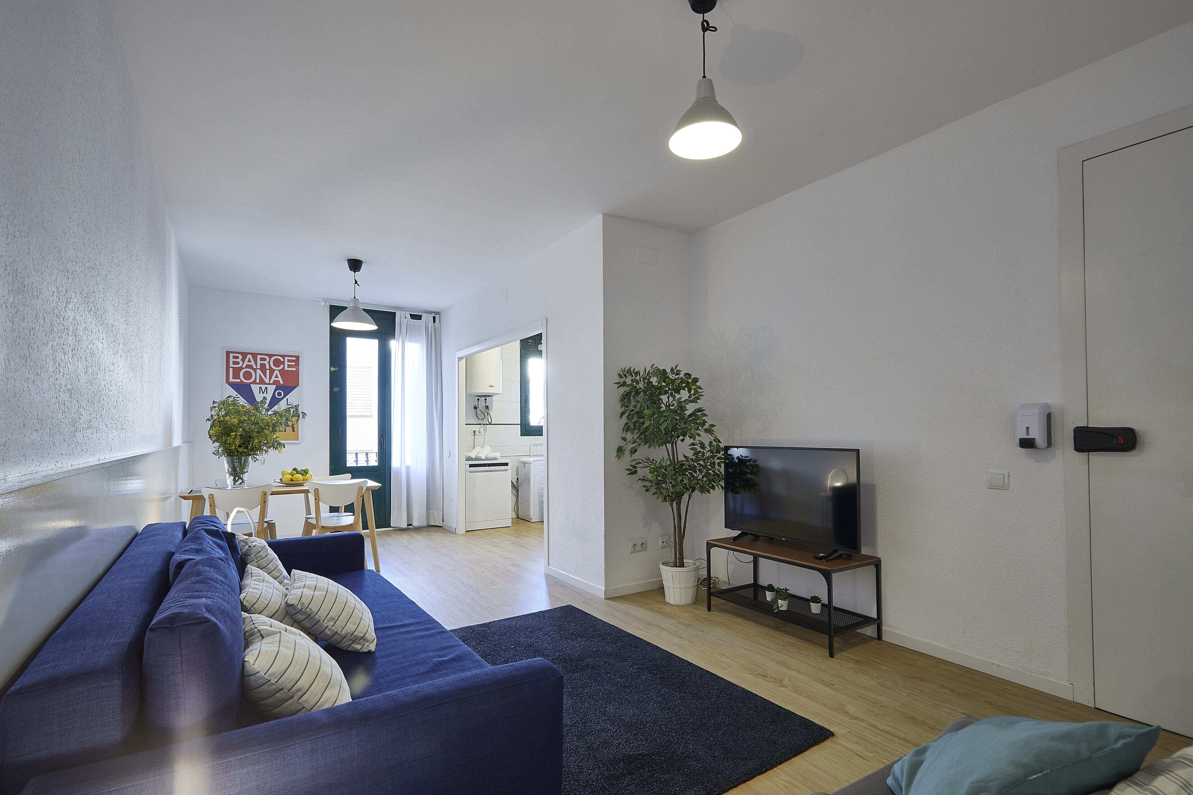 Un salon moderne avec un canapé, un téléviseur et une plante en pot.