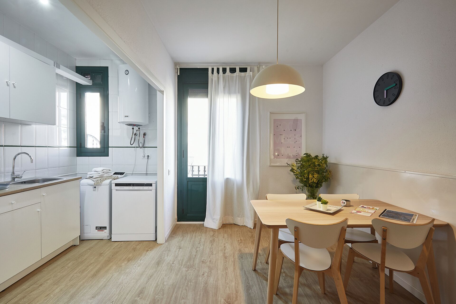 Eine moderne Küche mit weißen Schränken, einem Geschirrspüler und einem Essbereich mit einem Holztisch und Stühlen.