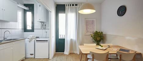 Eine moderne Küche mit weißen Schränken, einem Geschirrspüler und einem Essbereich mit einem Holztisch und Stühlen.