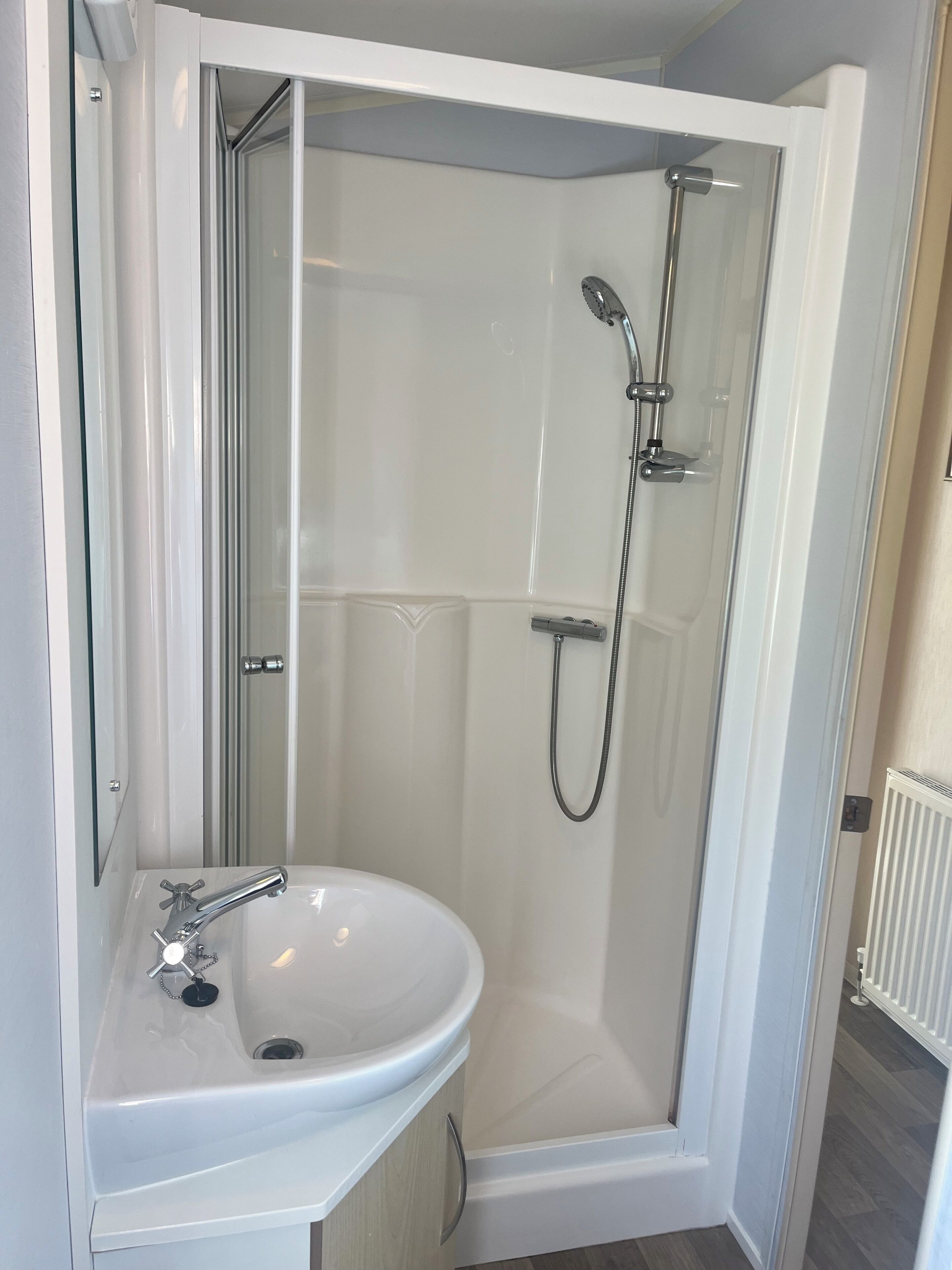 A modern bathroom with a glass-enclosed shower, a white sink, and a mirror.