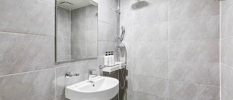 Un baño moderno con un lavamanos blanco, ducha y espejo.