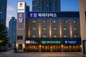 Un hotel con un letrero que indica Paradise Hotel, Olive Chicken y OnePick Game & Prize.