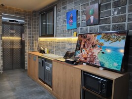 Cocina moderna con protector contra salpicaduras de pared de piedra, horno empotrado y un televisor de pantalla plana grande que muestra un paisaje.