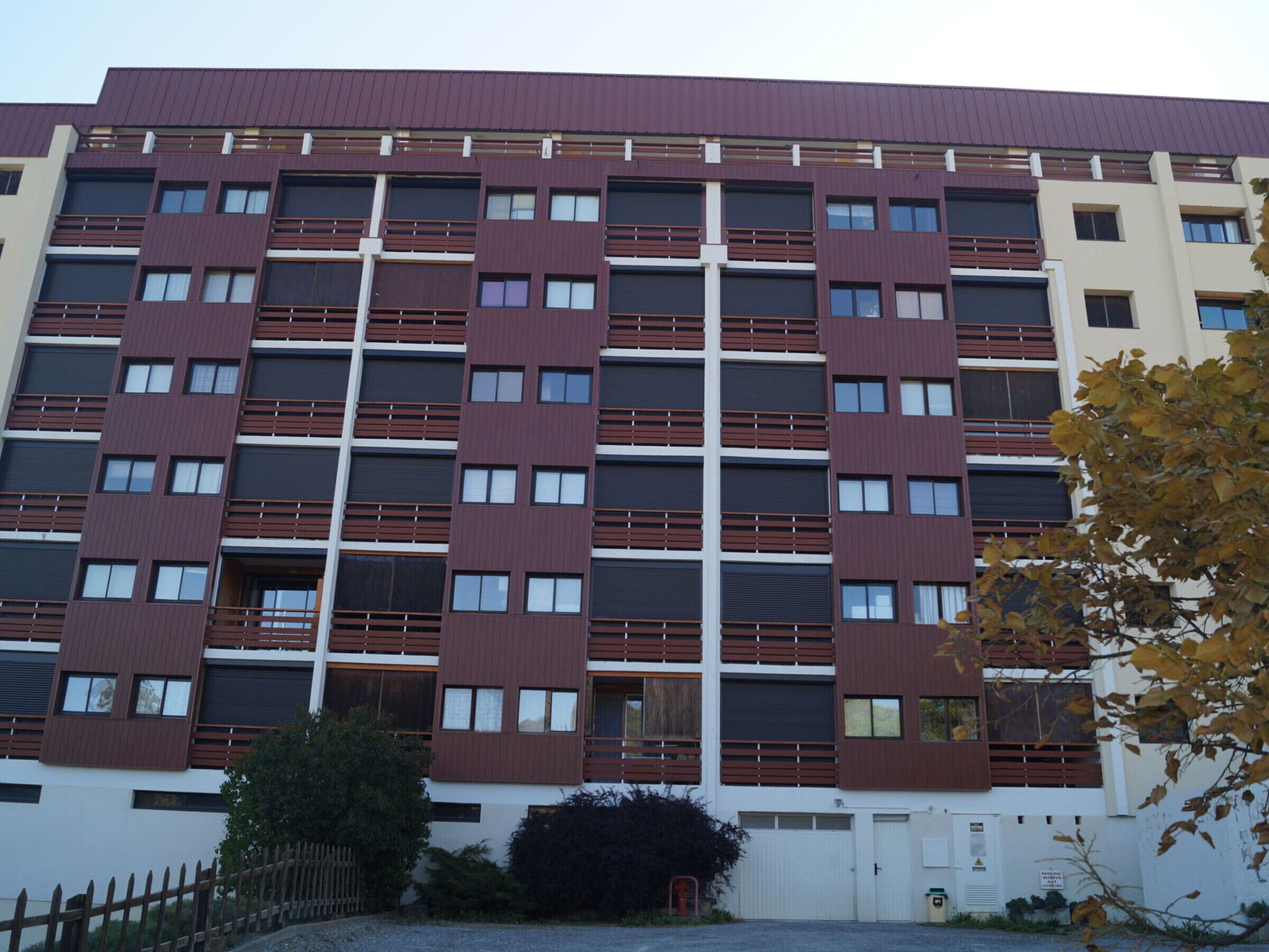 Ein mehrstöckiges Gebäude mit moderner Architektur, das eine Reihe von Balkonen und Fenstern aufweist.