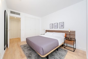 A bedroom with a bed, a bedside table, a wardrobe, and a door. - Plaza de Castilla 193 (Madrid)