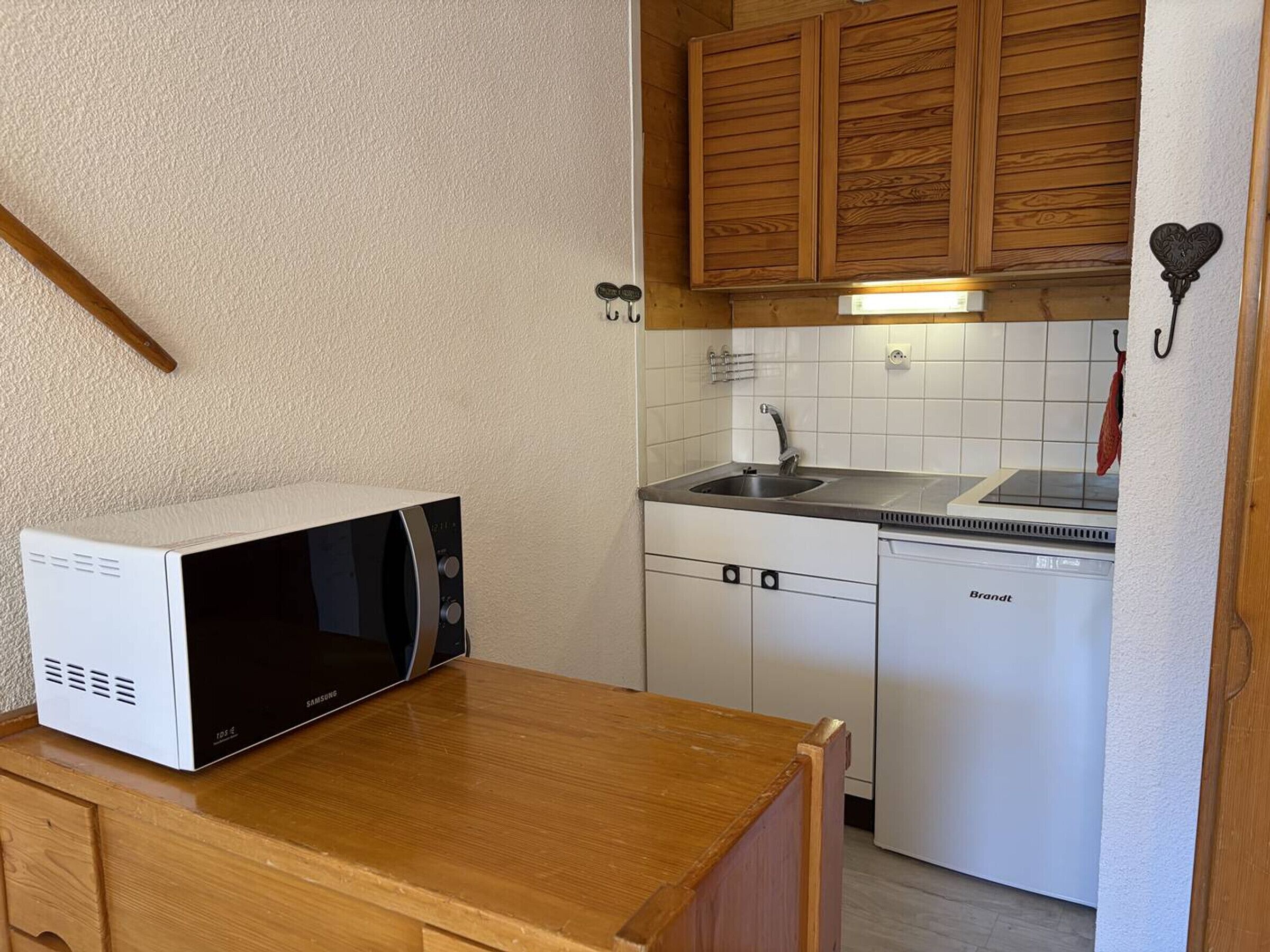 Eine kompakte Küche mit Mikrowelle, Spüle und Geschirrspüler von Brandt.