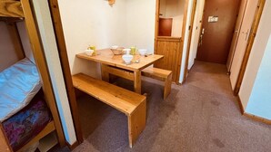 A compact room with a wooden table, benches, and a small kitchenette area. - Studio for 4 near slopes, balcony, pets allowed - Vallandry (Peisey-Vallandry)