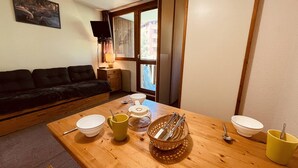 A cozy living room with a sofa, a dining table set with bowls, a coffee maker, and a window with a view of buildings. - Studio for 4 near slopes, balcony, pets allowed - Vallandry (Peisey-Vallandry)