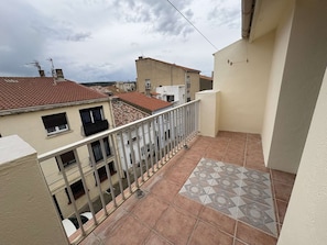 A balcony with a tiled floor, a metal railing, and a view of neighboring buildings.