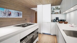 Una cocina moderna con techo de madera, armarios blancos y una isla central.